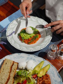 Top-down view of a stylish breakfast with avocado salad and poached egg.