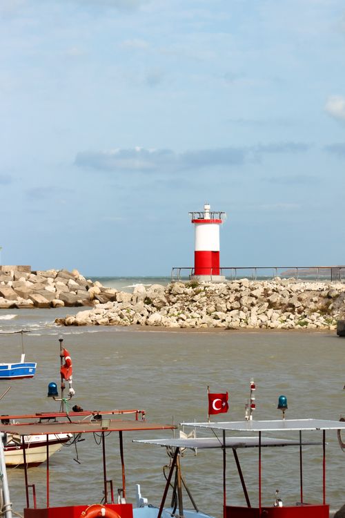 Free Calm seaside scene featuring a Turkish lighthouse with boats and a clear sky. Stock Photo