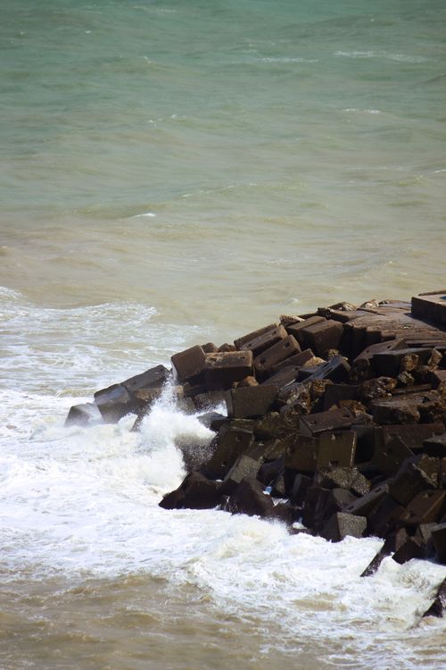 Free Concrete blocks on a breakwater with waves crashing in a vibrant coastal scene. Stock Photo