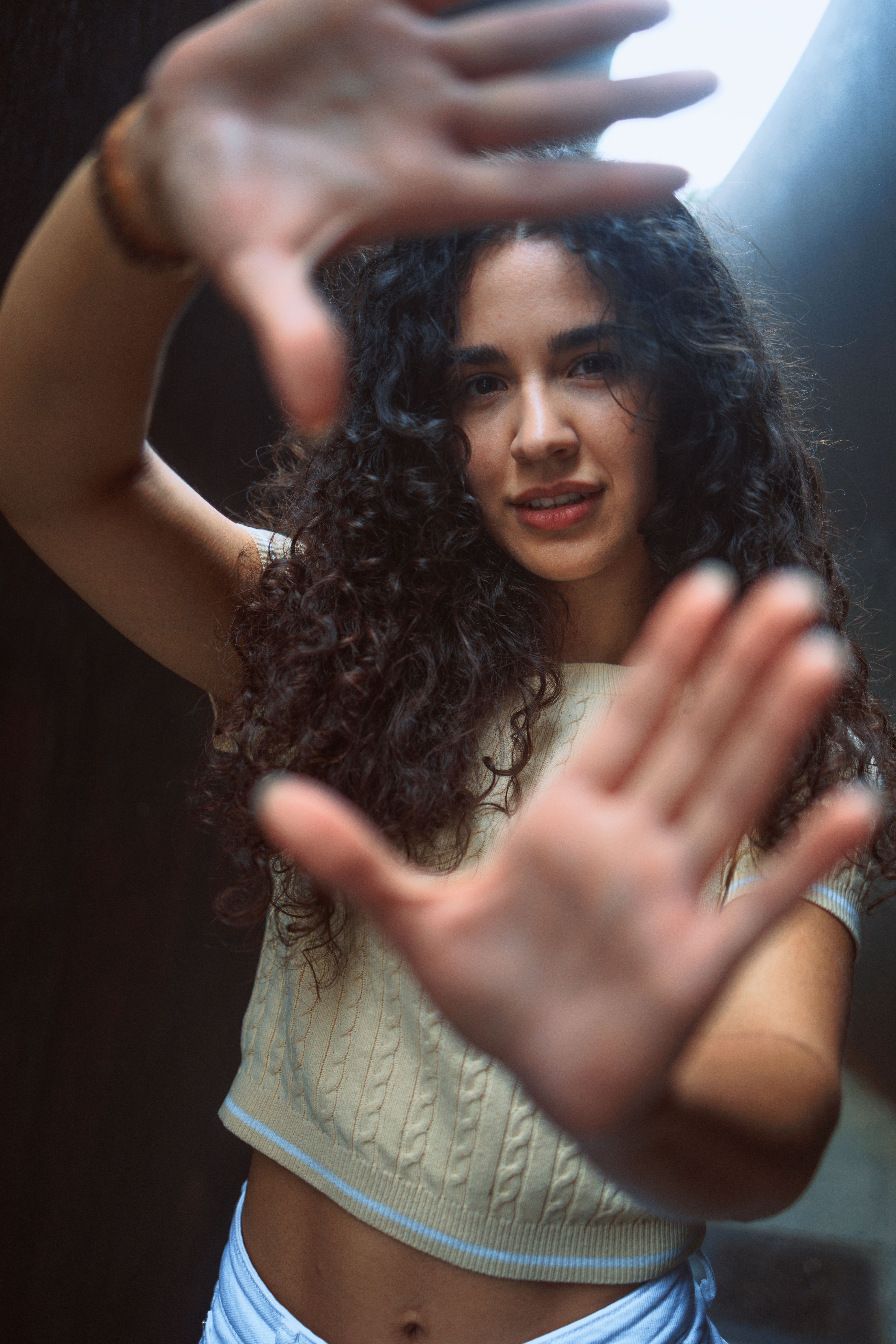 A young woman frames the camera with her hands, capturing a candid and artistic moment in Berlin.