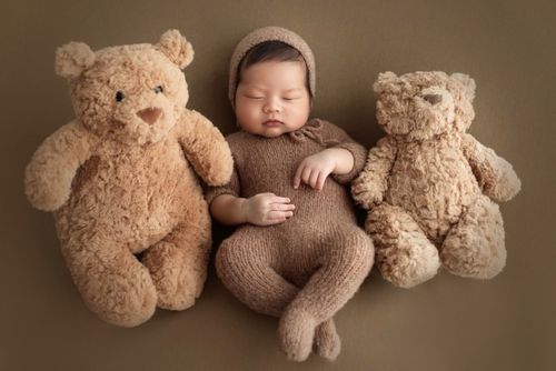 Free Adorable baby sleeps between two teddy bears, showcasing tender innocence and warmth. Stock Photo