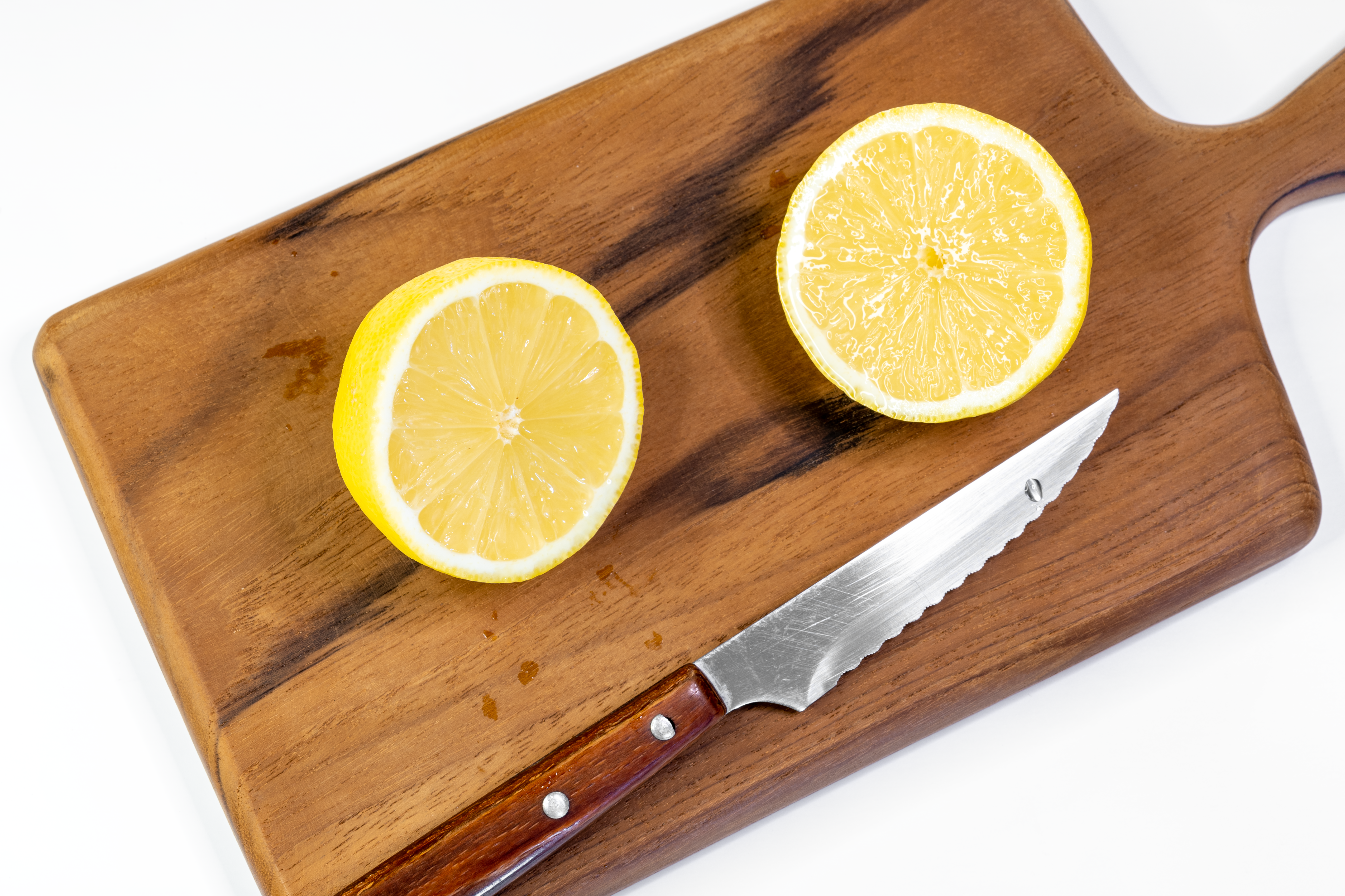 Sliced lemon halves on a wooden cutting board, perfect for food photography and culinary themes.