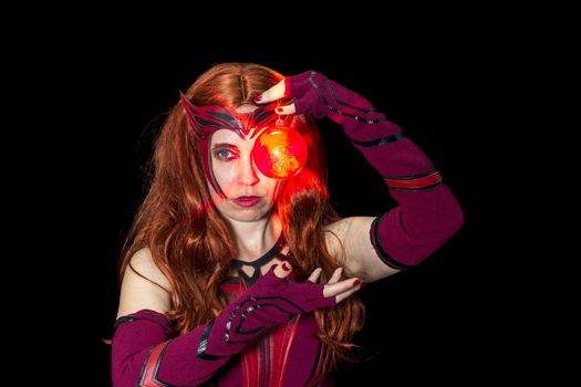 Powerful cosplay featuring a mystical character with red glowing energy orb on black background.