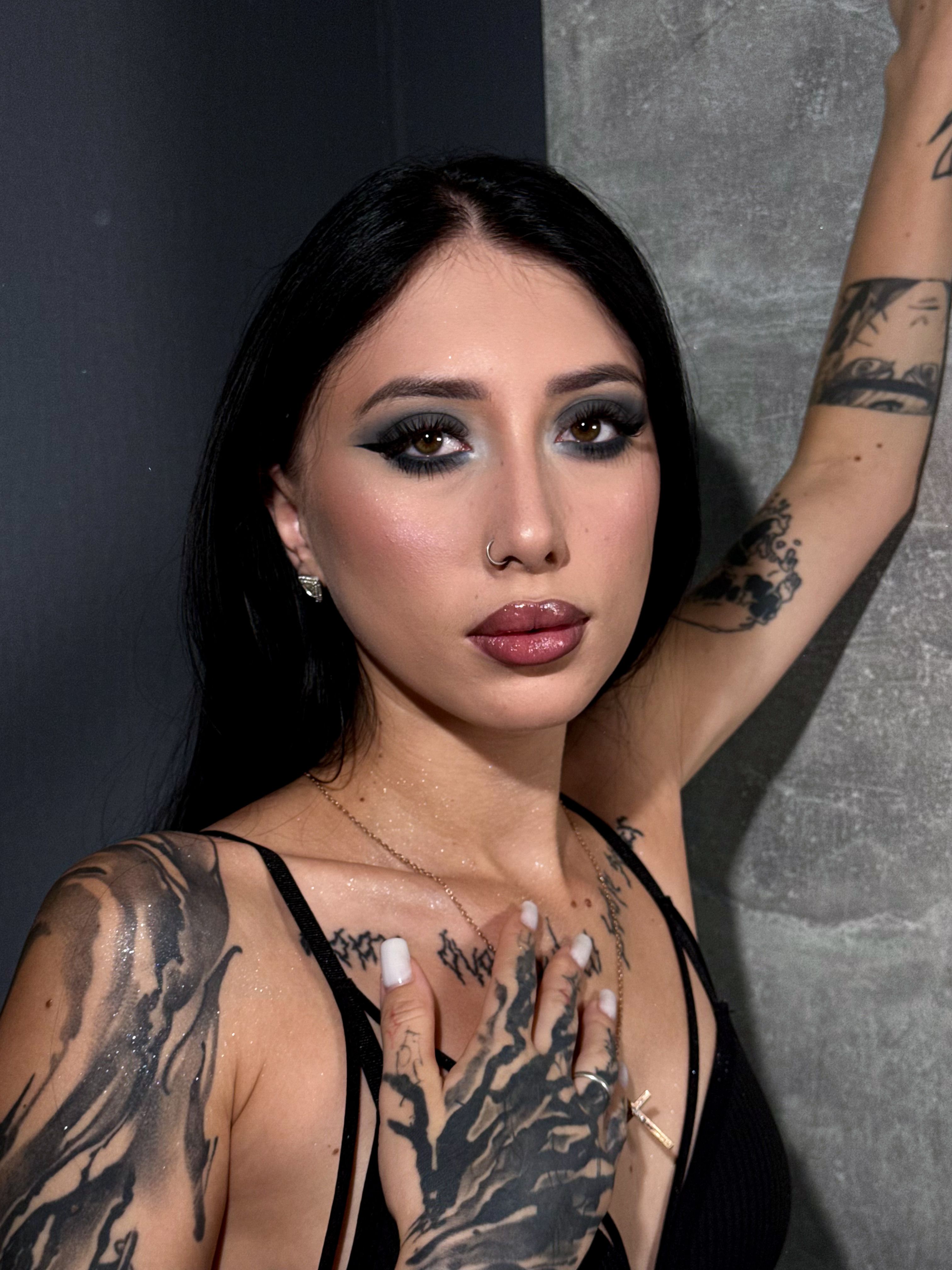 Close-up portrait of a woman with artistic tattoos and bold makeup.