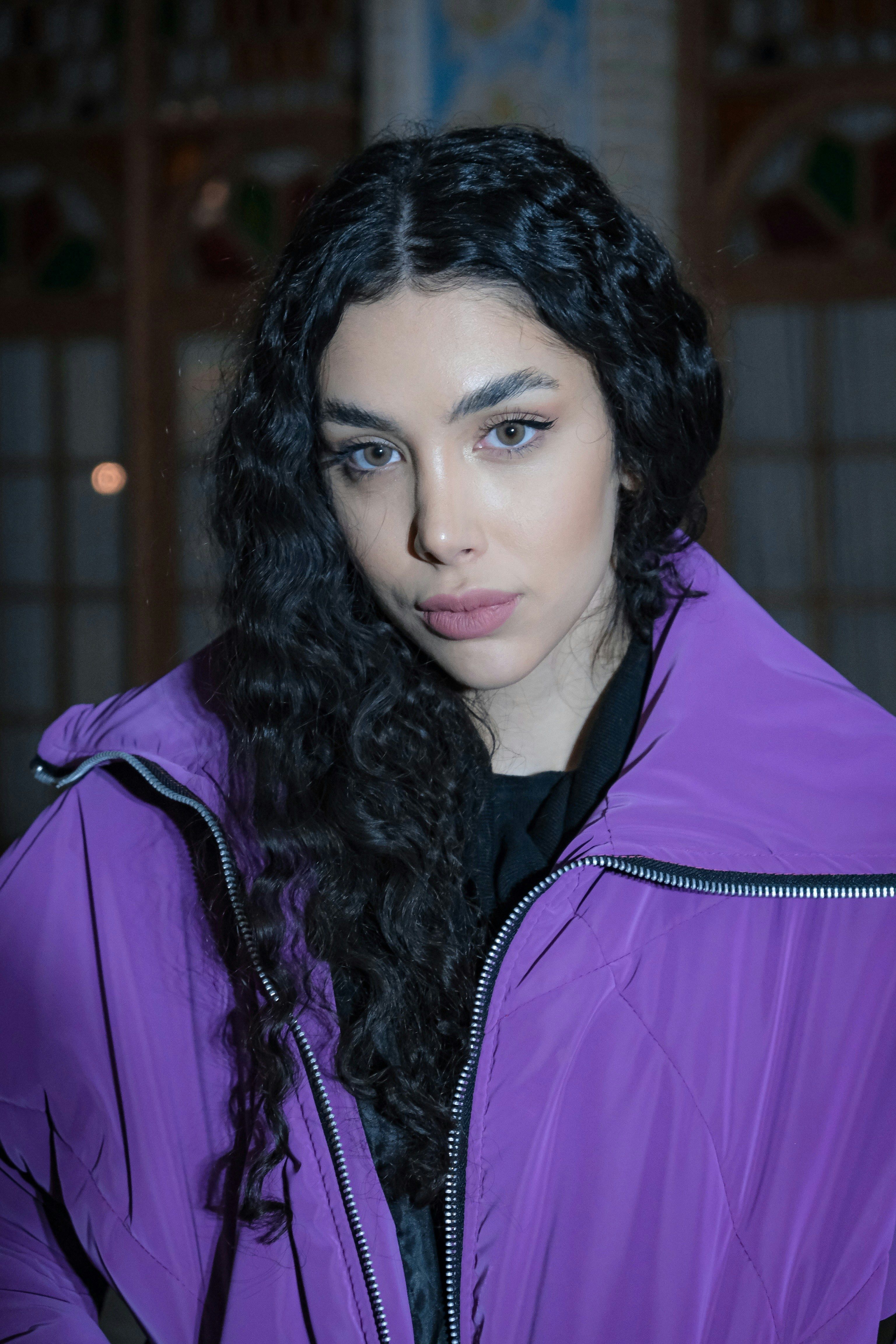 Portrait of a young woman wearing a purple jacket indoors, illustrating modern fashion.