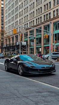 Sleek black sports car parked on a New York City street with towering skyscrapers in the background.