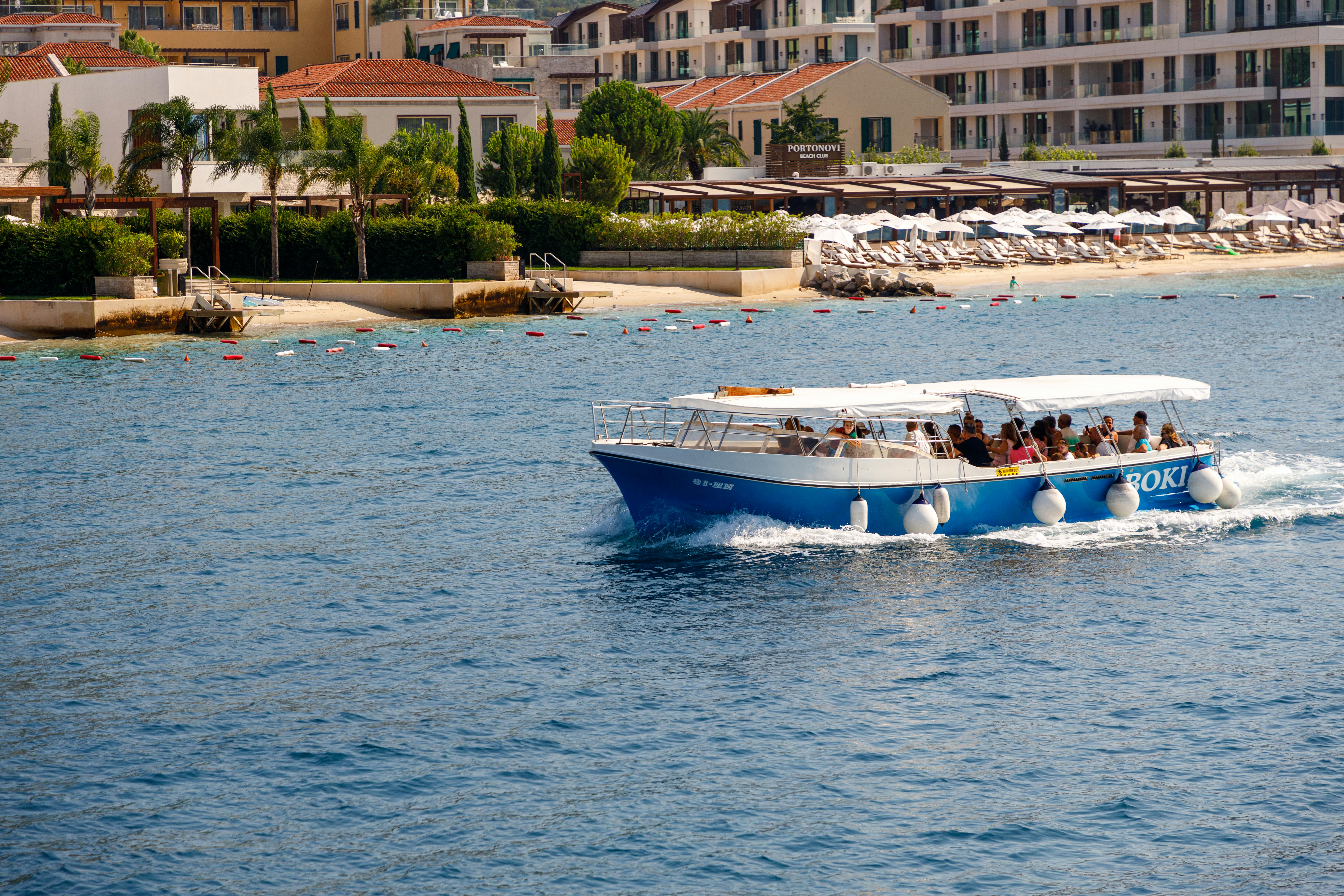 People enjoying a scenic cruise near Porto Montenegro in Herceg Novi on a sunny day.