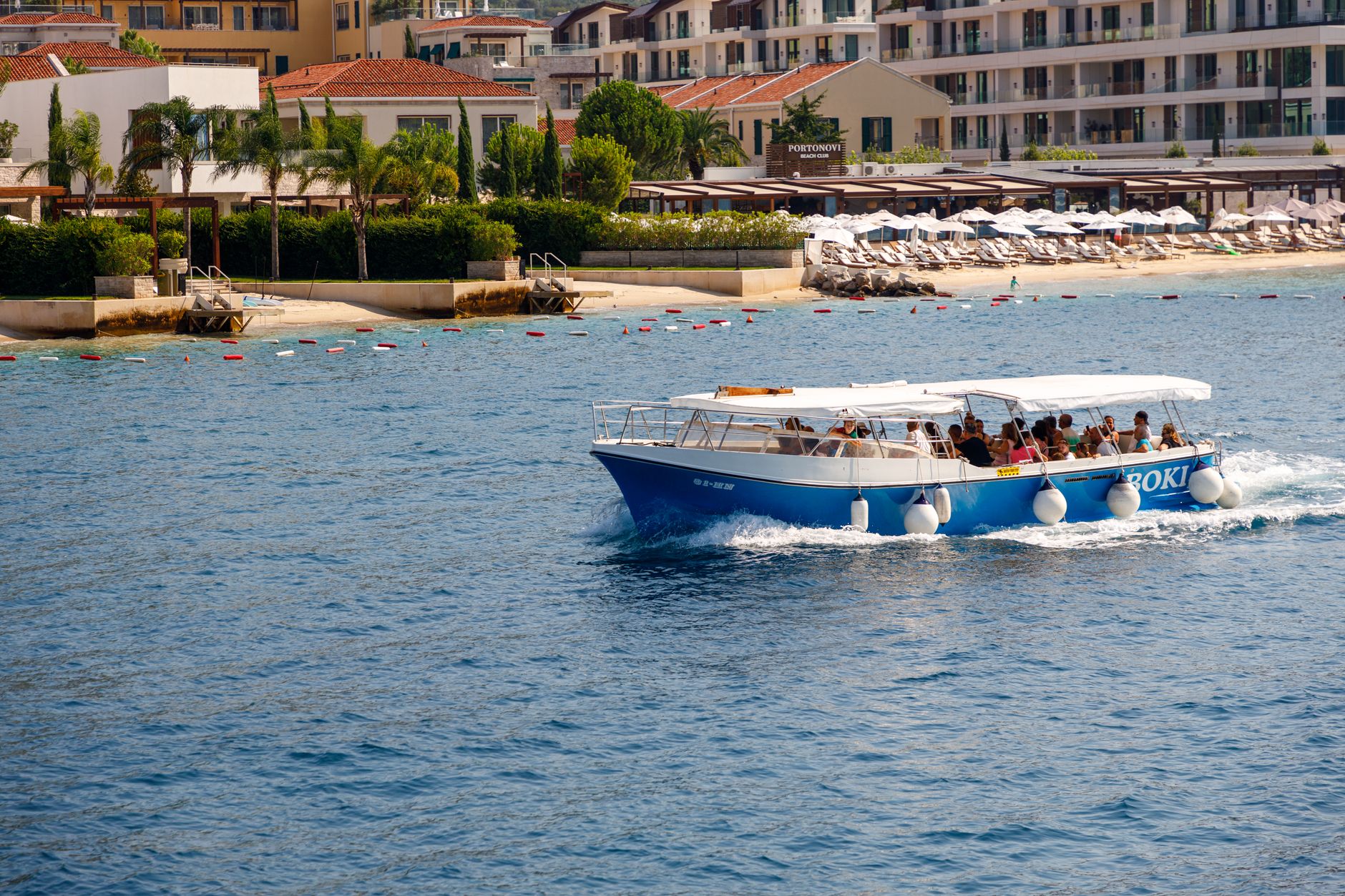 People enjoying a scenic cruise near Porto Montenegro in Herceg Novi on a sunny day.