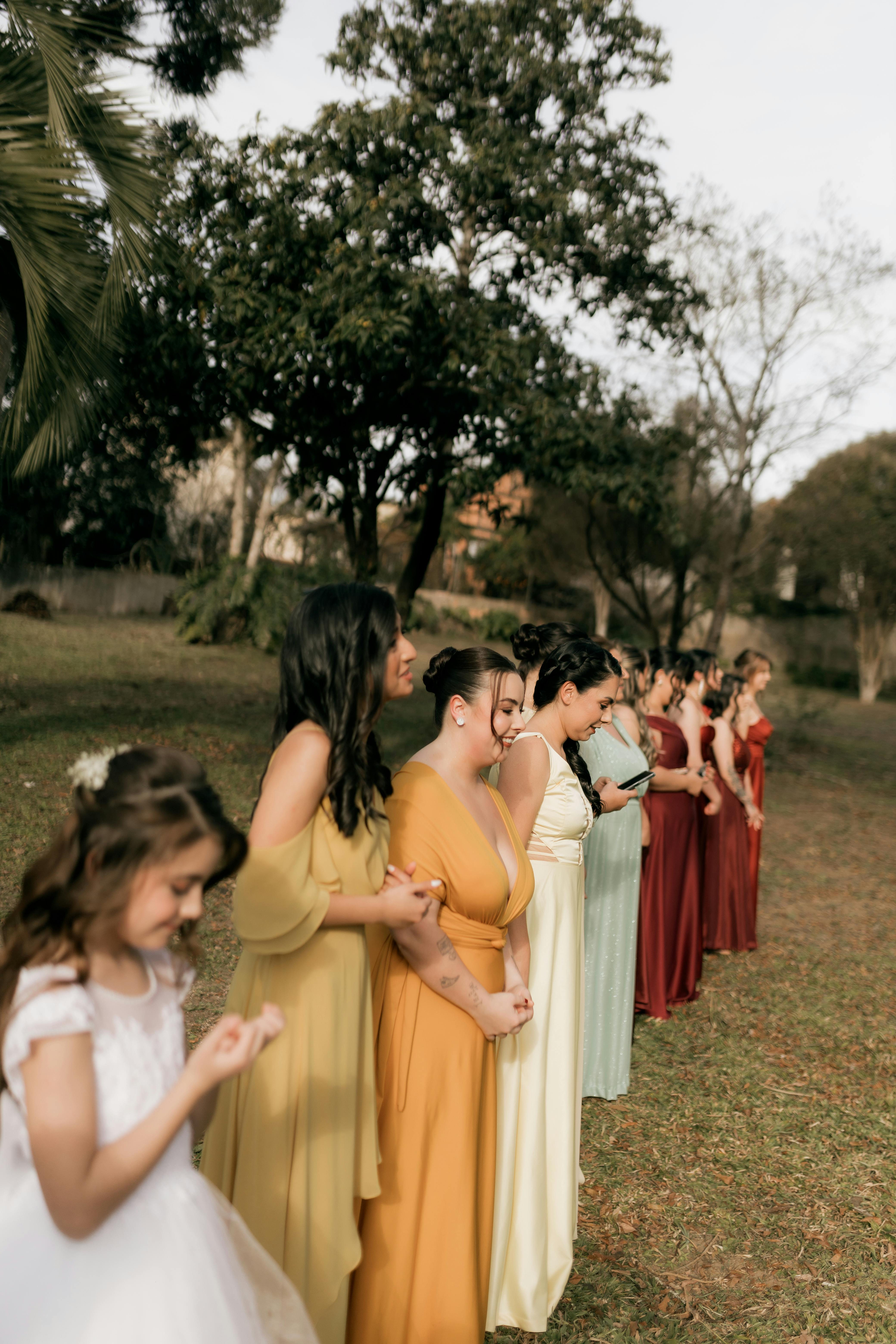 A lineup of bridesmaids in vibrant dresses attending an outdoor wedding ceremony.
