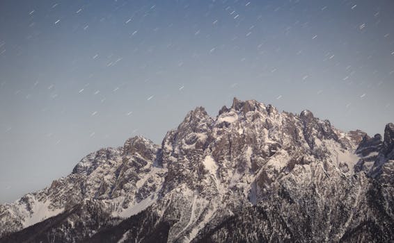 Long exposure captures star trails over snow-covered Dolomites in Italy.