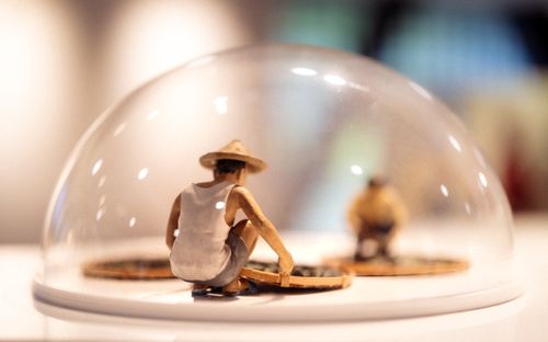 Free Close-up of a miniature worker figurine under a glass dome on display in a museum setting. Stock Photo