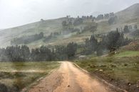 Dirt road cutting through a rainy mountainous landscape in rural Peru.