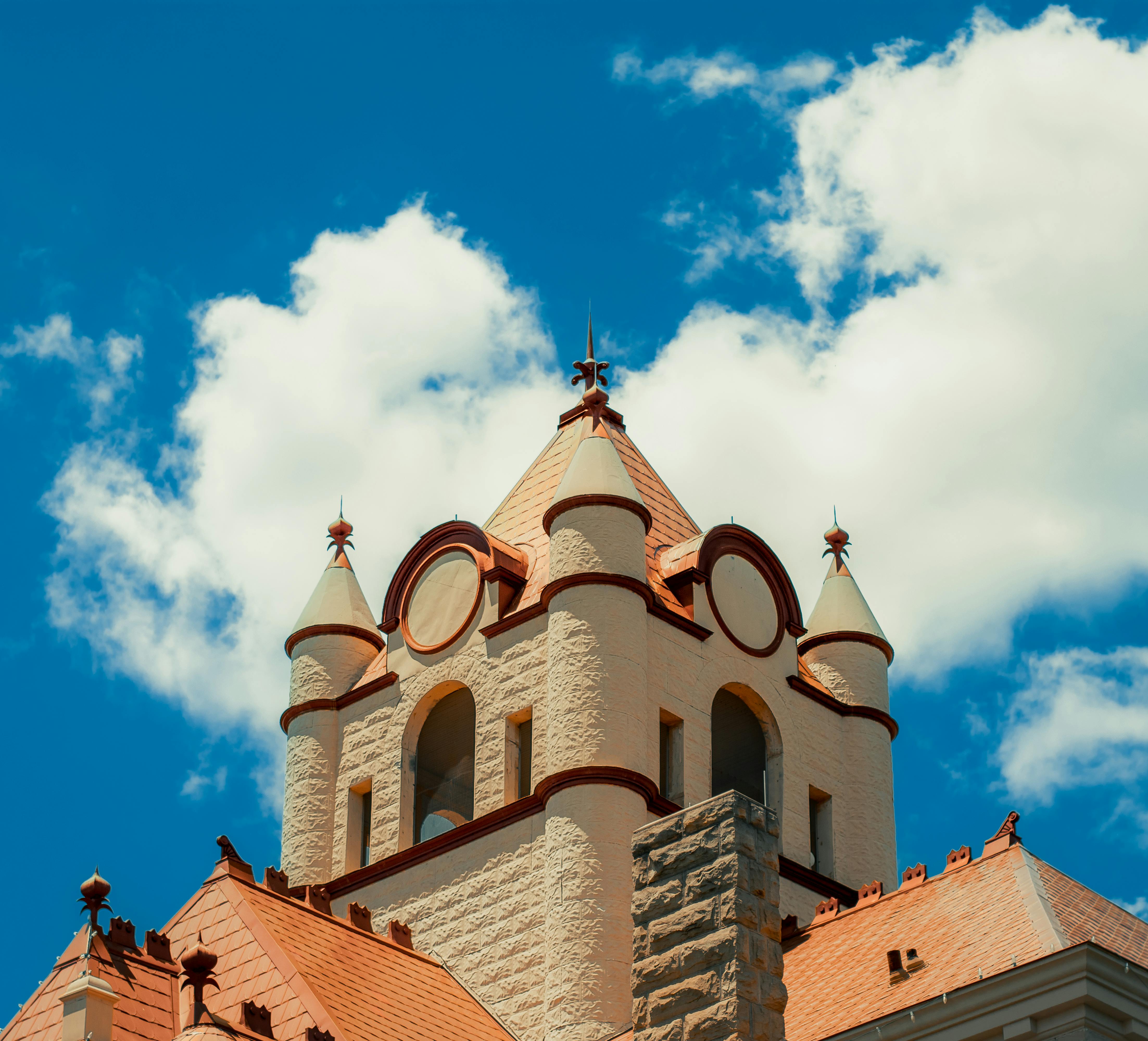 A stunning historic building in Brady, Texas with a vibrant red roof against a blue sky and white clouds.