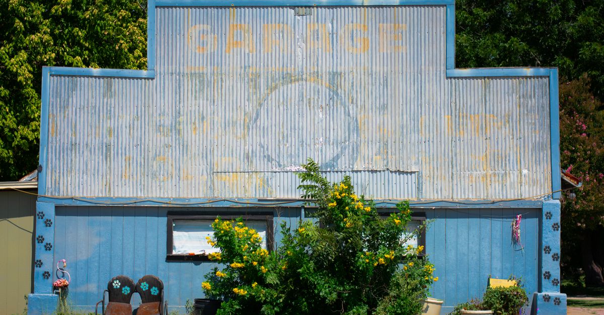 Colorful vintage garage with greenery in Brady, Texas. Ideal for retro and architectural themes.