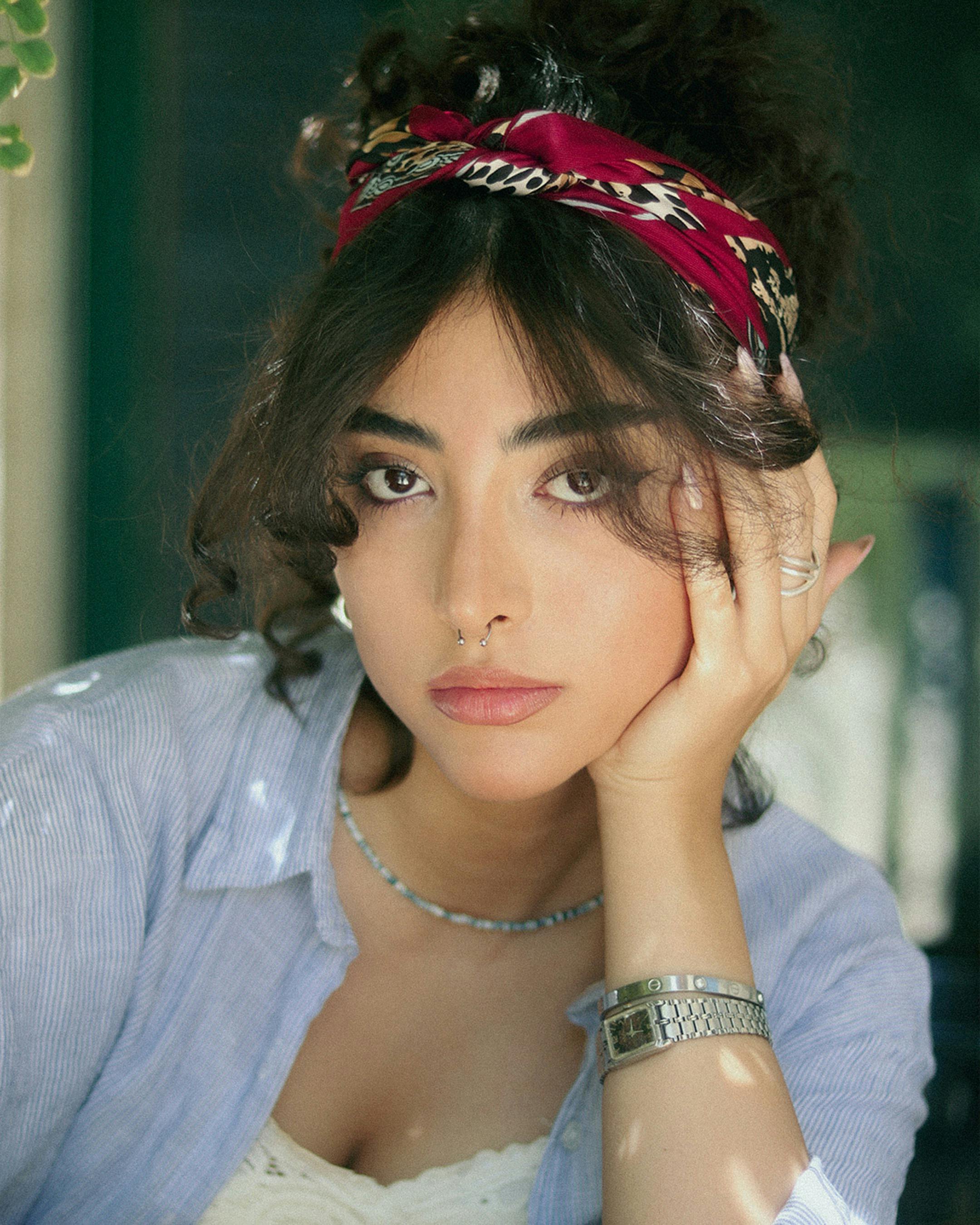 Portrait of a young woman wearing a red headband, looking thoughtfully at the camera.