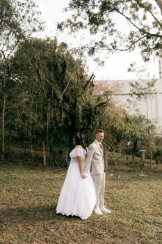 Bride and groom elegantly holding hands in a lush garden setting, ideal for romantic themes.