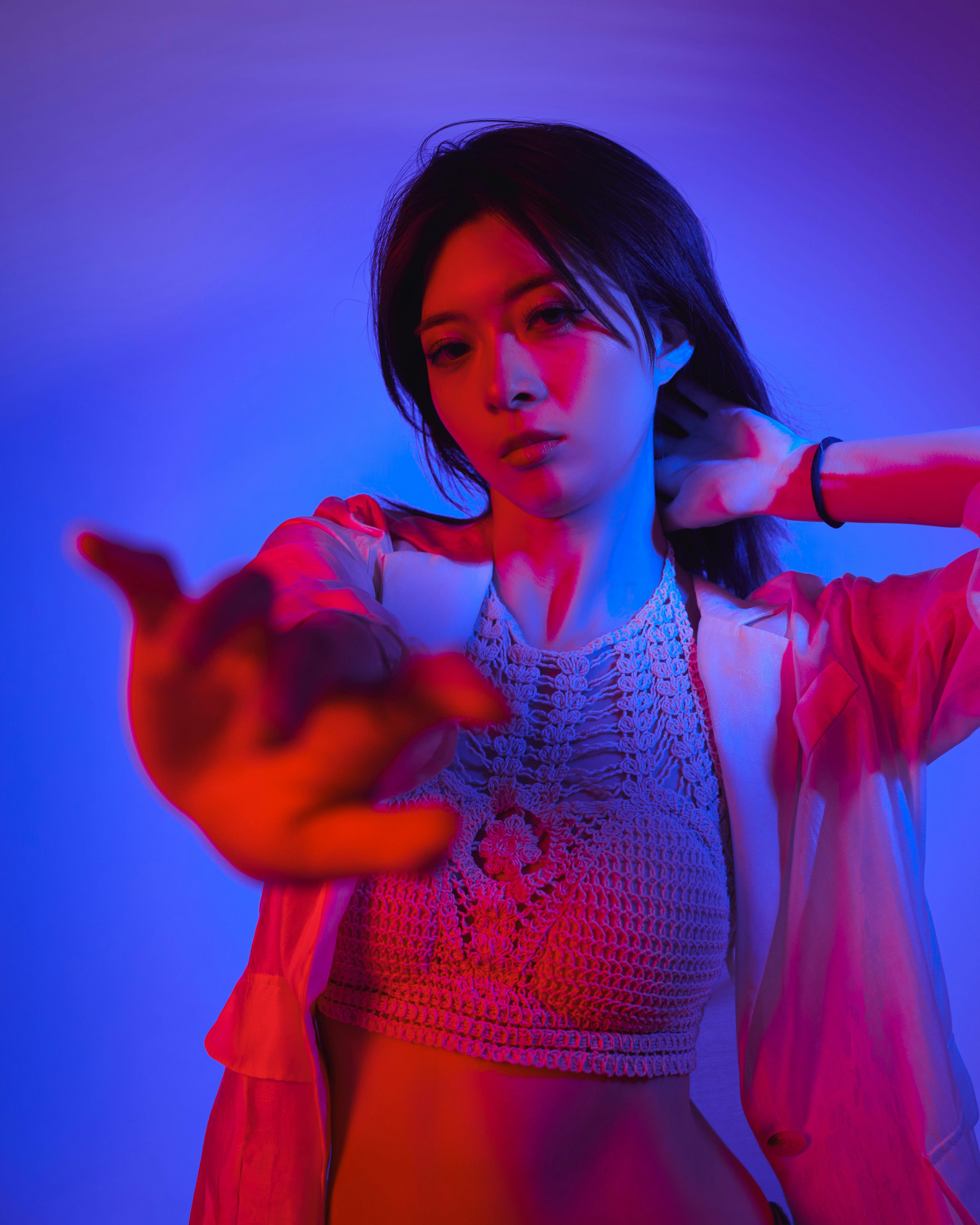 Artistic portrait of a woman under blue and red lighting, evoking a modern and dramatic mood.