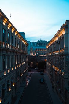 Serene twilight view of an empty urban street with illuminated classic buildings.