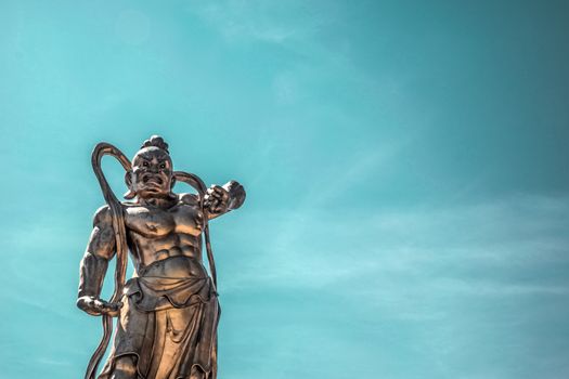A striking bronze statue of an ancient warrior with a deep blue sky backdrop.