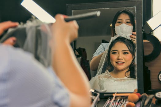 A bride being prepared by a hairstylist in a makeup studio, reflecting joy.