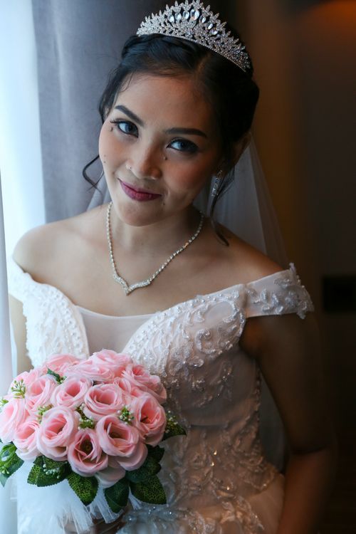 Free A beautiful bride with a tiara and bouquet of pink roses in an indoor setting, radiating joy. Stock Photo