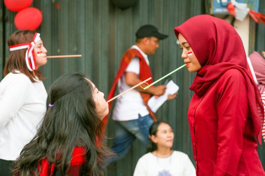 Three women and a man play a fun straw game outdoors, adding cheer to the festive atmosphere.