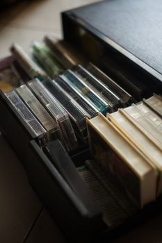 A variety of cassette tapes neatly organized in a black storage box, depicting nostalgia and retro music culture.