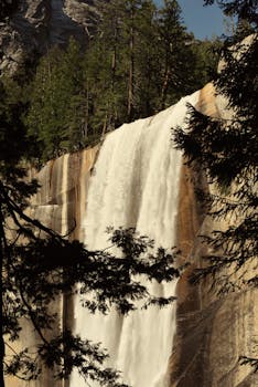 Captivating view of Vernal Fall in Yosemite, framed by lush trees and rugged cliffs.