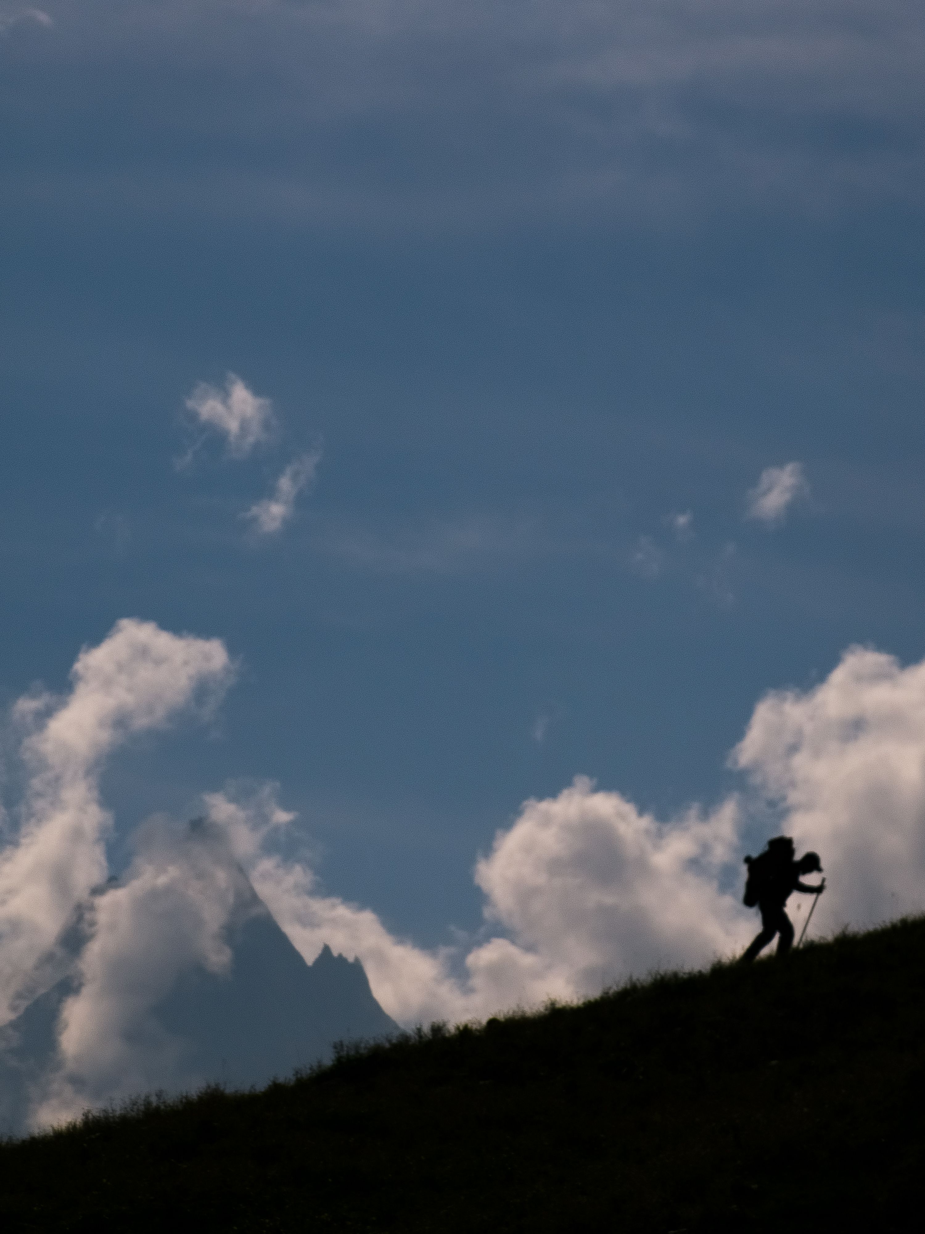 Man hiking up a sloped hill in the distance