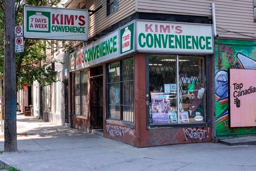 Street view of iconic Kim's Convenience store in urban setting with graffiti art.