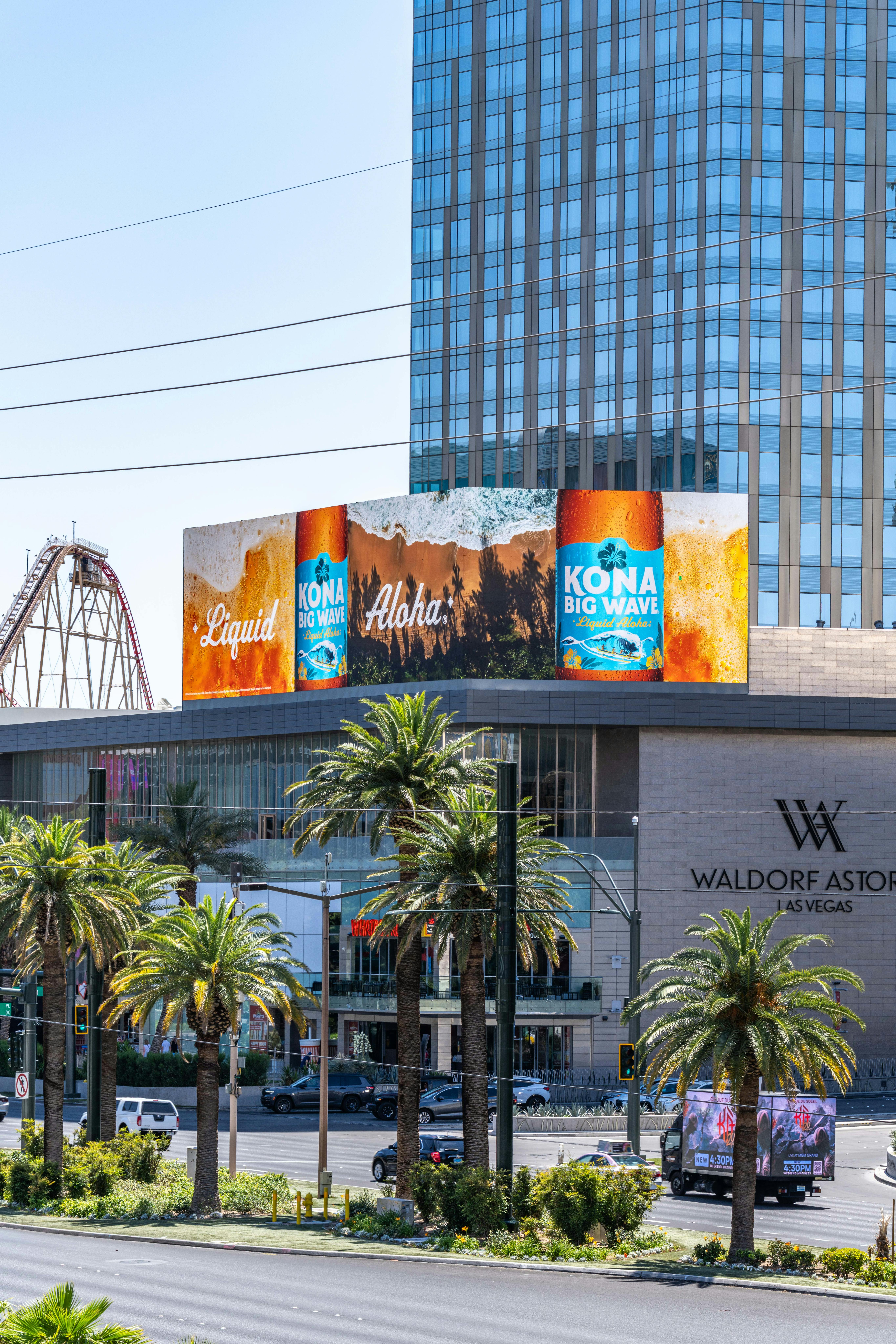 A vibrant Kona Big Wave beer advertisement outside the Waldorf Astoria on the iconic Las Vegas Strip.