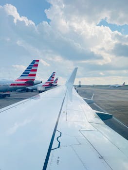View of airplane wing at Charlotte Airport with cloudy sky and aircrafts on the ground.