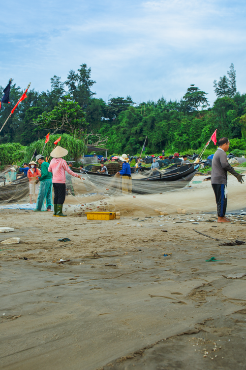Free Fishermen and women working with nets on a scenic beach. Stock Photo