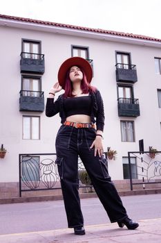 Fashionable woman in trendy attire posing confidently with urban backdrop.
