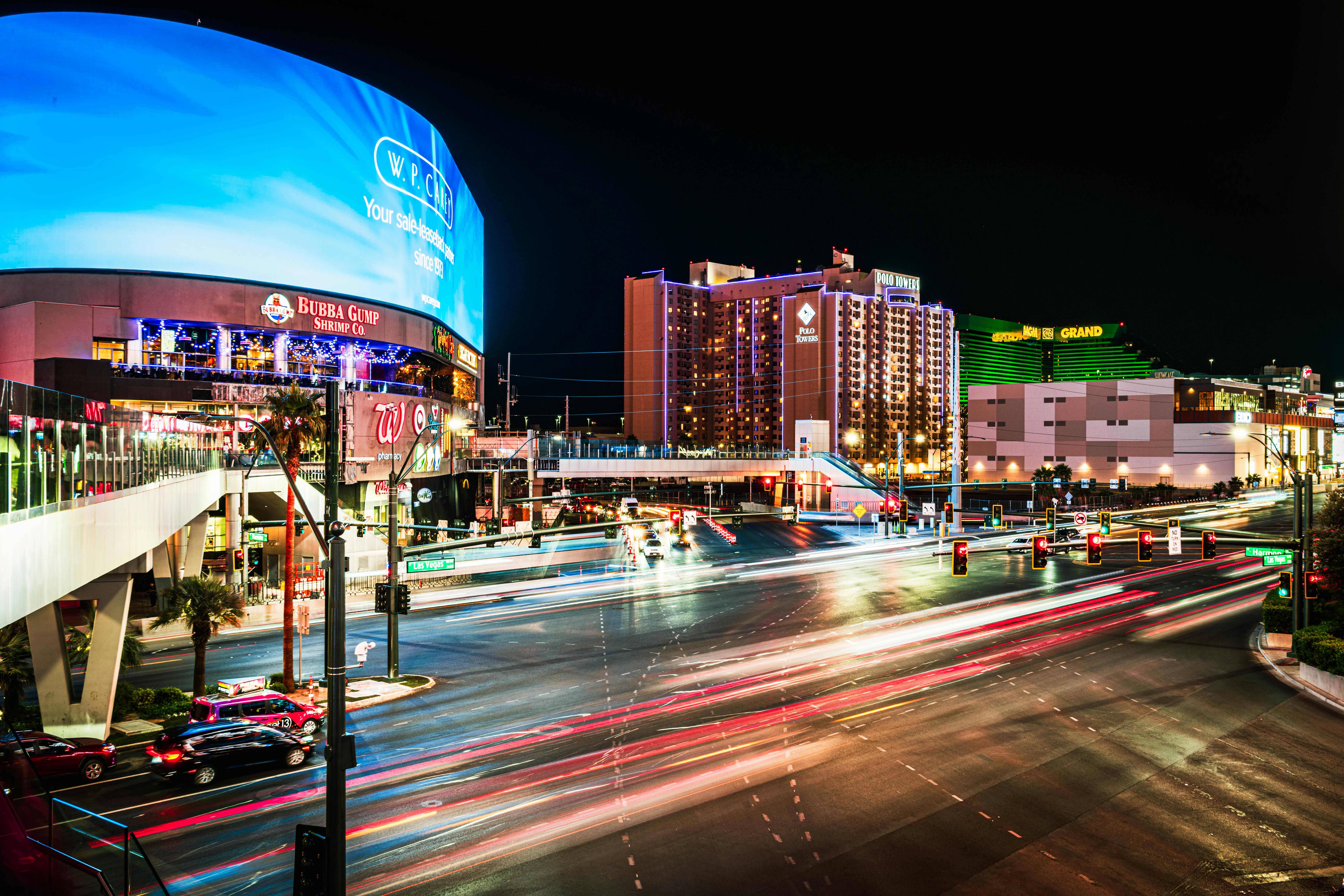 Dynamic night view of Las Vegas Boulevard featuring light trails and vibrant city lights.