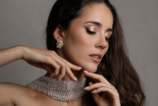 Close-up portrait of a stylish woman wearing pearl jewelry and makeup.