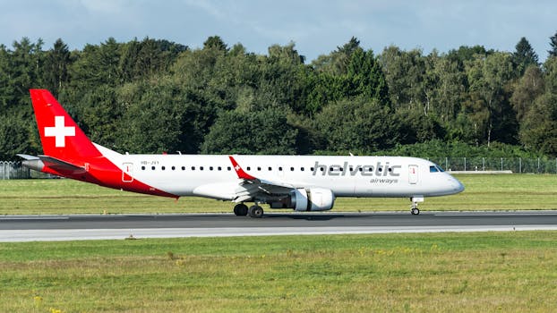 Helvetic Airways airplane taxiing at Hamburg Airport on a sunny day.