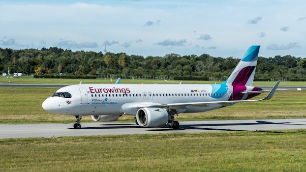 Eurowings Airbus A320neo on taxiway at Hamburg Airport, a clear summer day with scenic background.