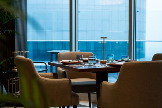 Sophisticated dining table with glassware in a chic restaurant setting offering a city view.