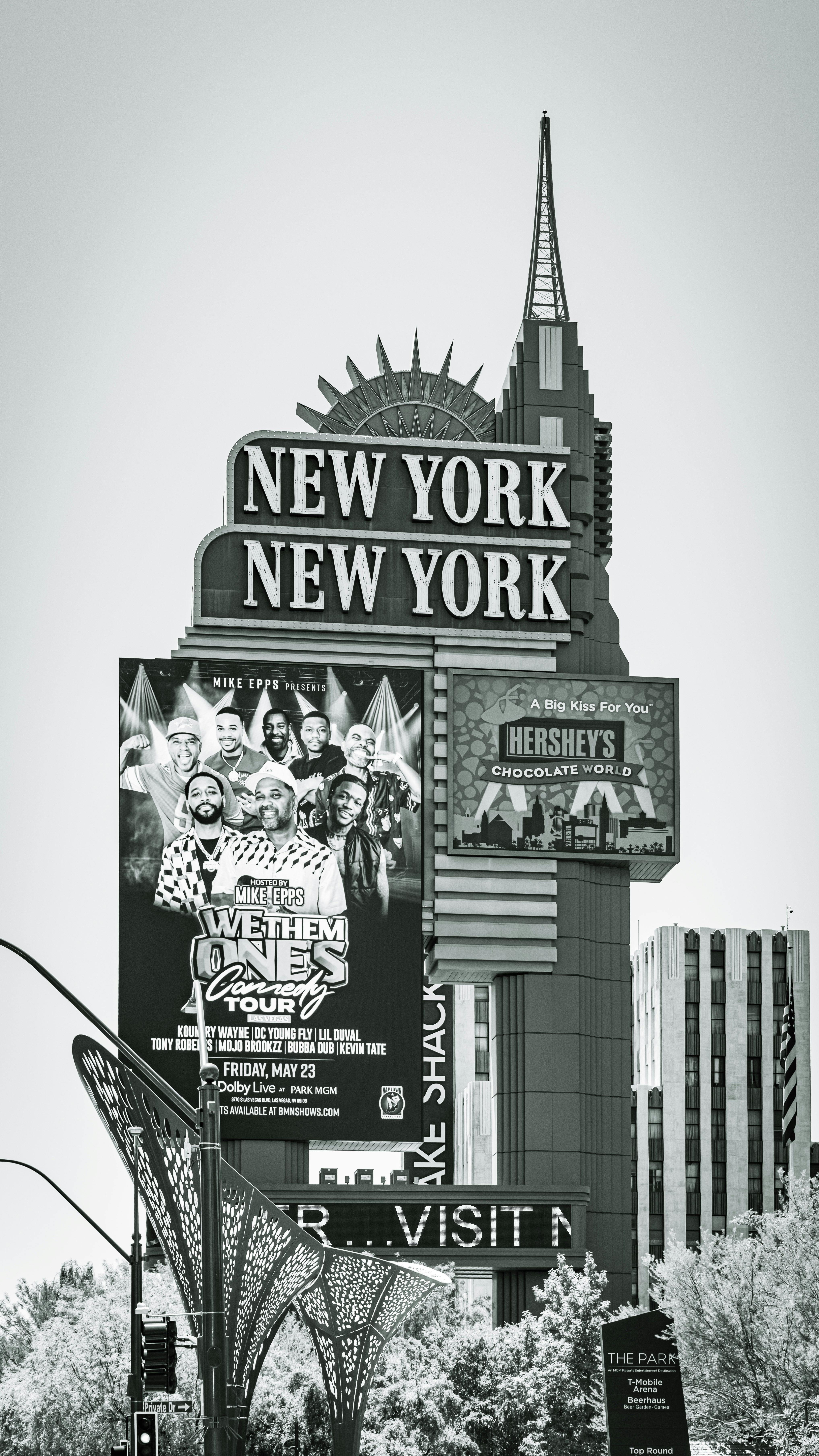 Black and white photo of the New York New York Hotel sign in Las Vegas showcasing a comedy tour poster.