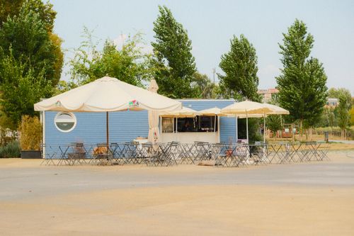 Free Charming outdoor cafe with umbrellas and empty seating surrounded by trees. Stock Photo