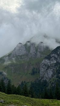 Scenic view of misty peaks shrouded in clouds and lush greenery, capturing nature's beauty.