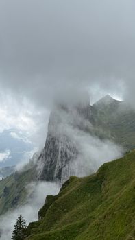Dramatic mountain peak shrouded in mist and clouds, creating an ethereal landscape.