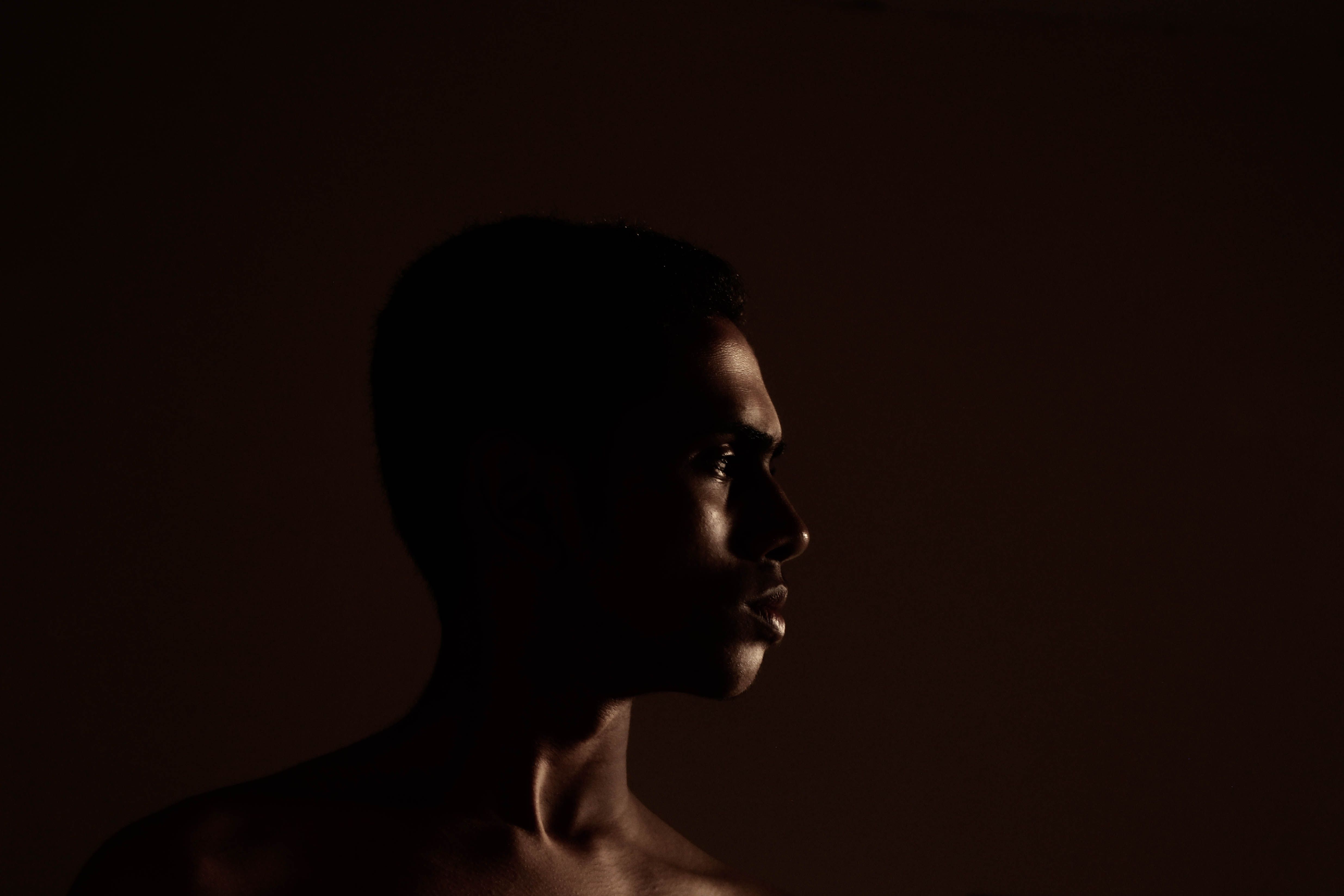 A striking low-key portrait of a young man in profile with dramatic lighting.. striking, portrait, young