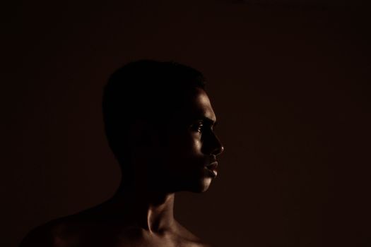 A striking low-key portrait of a young man in profile with dramatic lighting.. striking, portrait, young