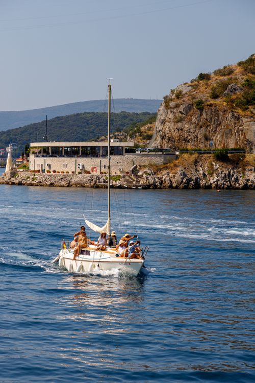 Free A group enjoys sailing on a sunny day near rocky Mediterranean coastline. Stock Photo