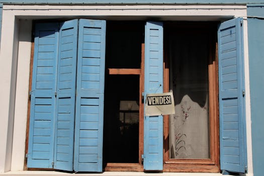 Elegant blue shutters on a Venice building with a 'For Sale' sign, capturing classic Italian charm.