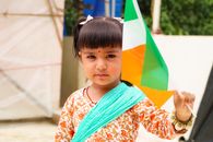 Portrait of a cute child holding the Indian flag outdoors, celebrating national pride.