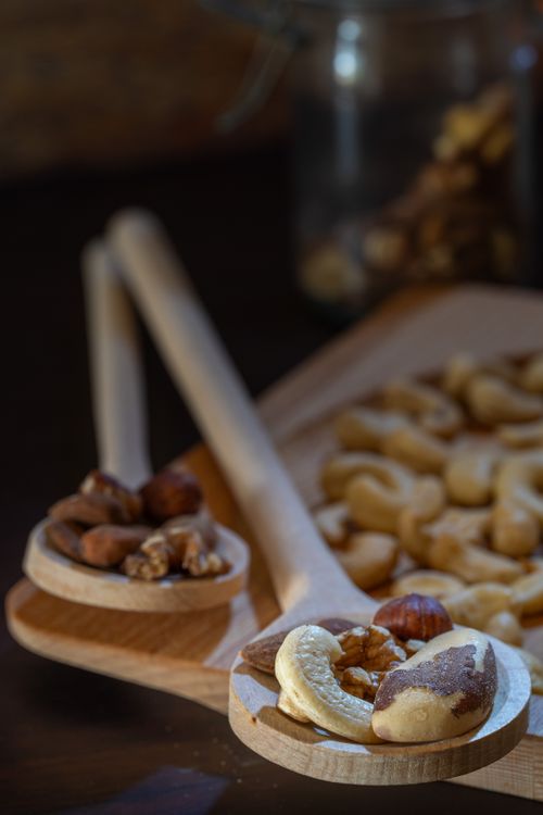 Free Close-up of assorted nuts on wooden spoons and chopping board, highlighting healthy snacks and protein sources. Stock Photo