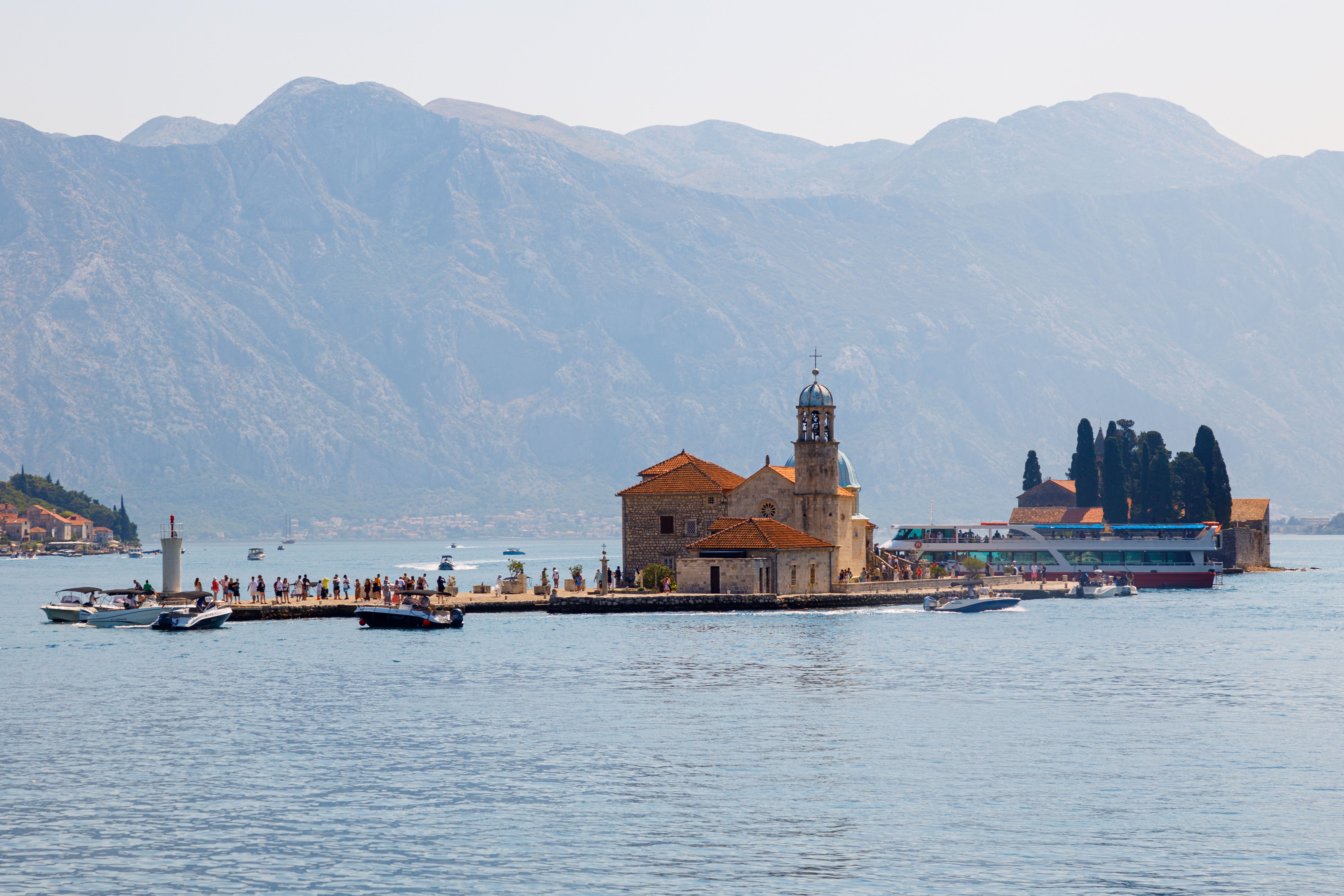 A stunning view of Our Lady of the Rocks island with mountains in the background, located in Montenegro.